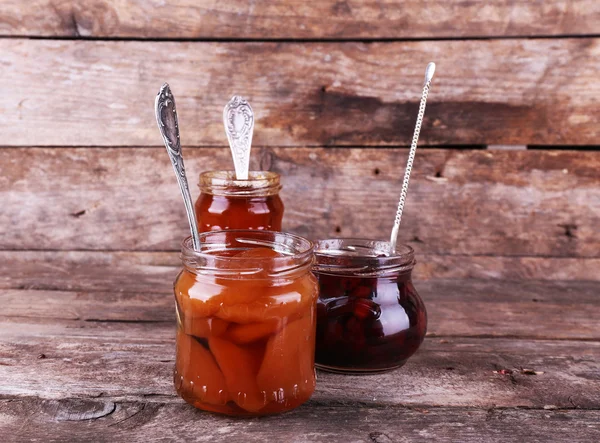 Jars of tasty jam on wooden background — Stock Photo, Image