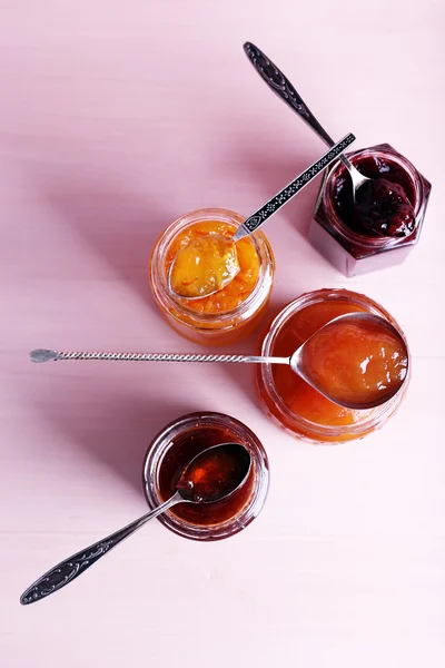 Jars of tasty jam on wooden background — Stock Photo, Image