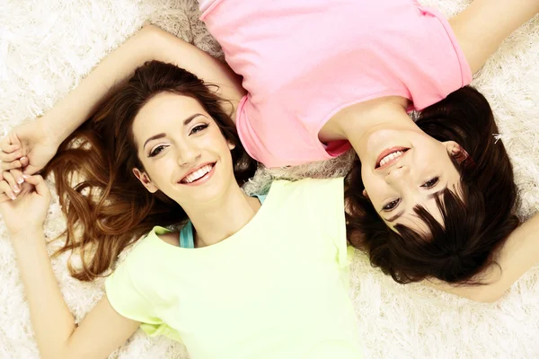 Дві дівчини лежать на пухнастому білому килимі, вид зверху — стокове фото