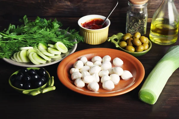 Queso mozzarella con aceitunas y verduras sobre fondo de madera —  Fotos de Stock