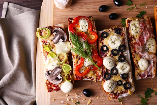 Panini diversi con verdure e formaggio sul tagliere in tavola da vicino — Foto Stock