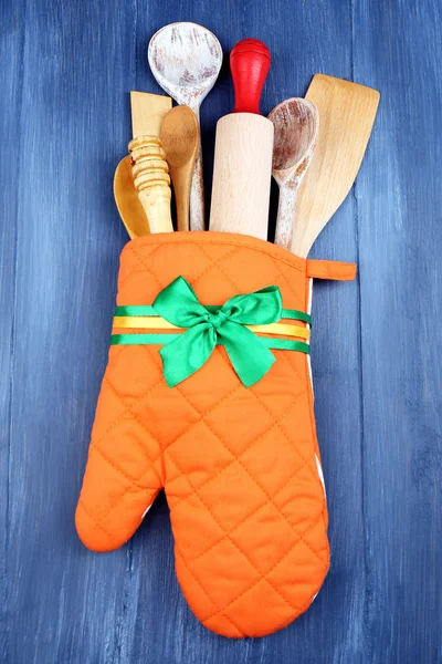 Different kitchen utensils in potholder on wooden background — Stock Photo, Image