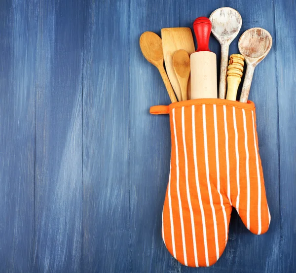 Different kitchen utensils in potholder on wooden background — Stock Photo, Image