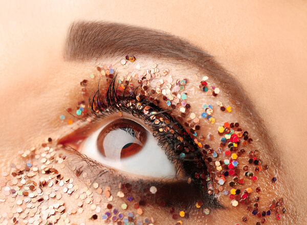 Female eye with fancy glitter makeup, macro view