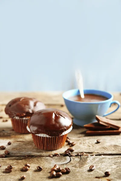 Bolos de chocolate caseiros saborosos e xícara de café na mesa de madeira, no fundo leve — Fotografia de Stock