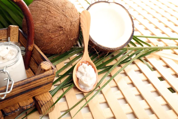 Kokos met blad en kokosolie in pot op houten achtergrond — Stockfoto