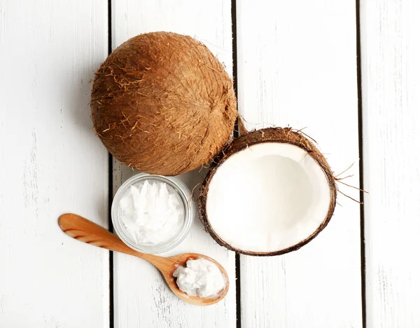 Kokos met kokosolie in pot op houten achtergrond — Stockfoto