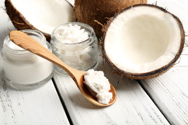 Coconut with jars of coconut oil and cosmetic cream on wooden background