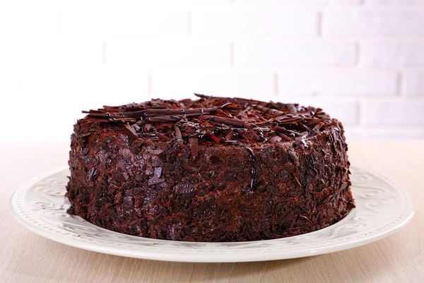 Tasty chocolate cake on table on brick wall background — Stock Photo, Image