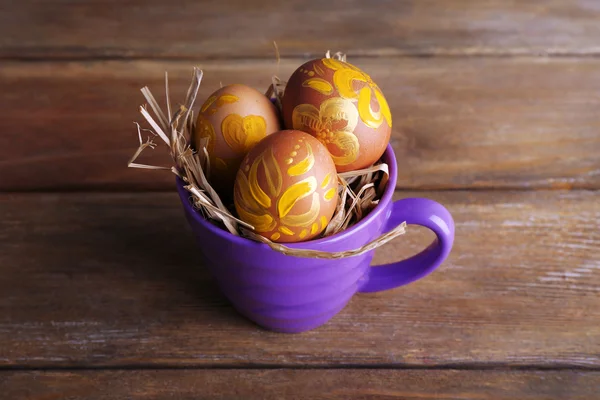 Påskägg i mugg på trä bakgrund — Stockfoto