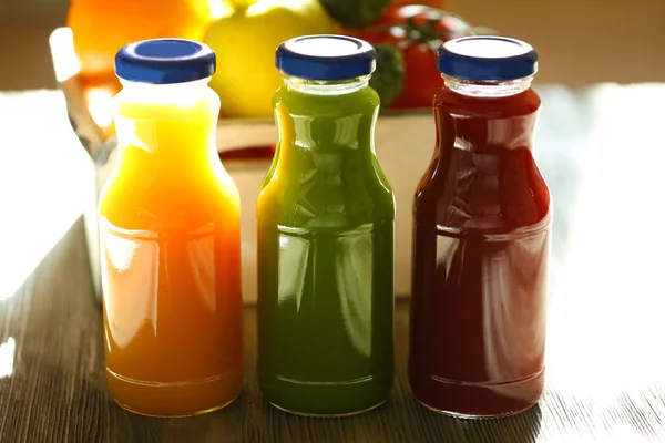 Bottles of juice with fruits and vegetables on table close up — Stock Photo, Image