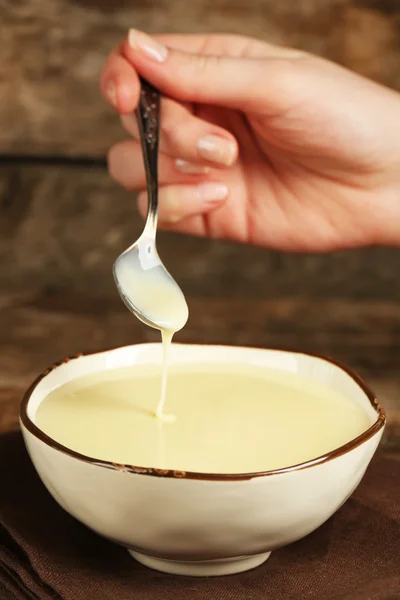 Kom met gecondenseerde melk en lepel op tafel close-up — Stockfoto