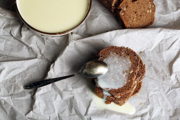 Potongan roti dengan susu kental pada latar belakang kertas — Stok Foto