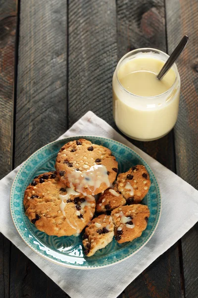 Cookies on plate with jar of condensed milk on wooden background