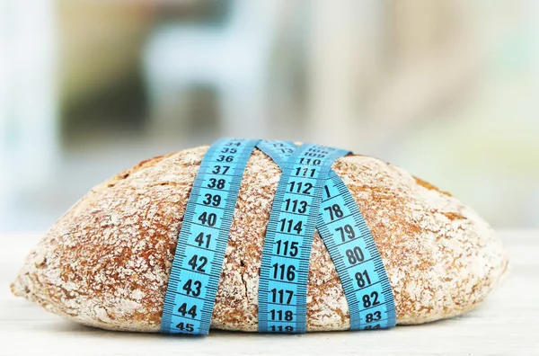 Pão fresco com fita métrica, em mesa de madeira- conceito de dieta — Fotografia de Stock