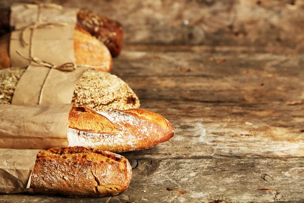 Different fresh bread, on old wooden table — Stock Photo, Image