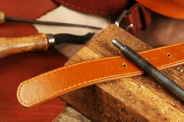 Craft tools with leather belt on table close up — Stock Photo, Image