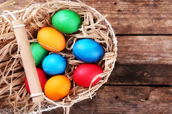 Easter eggs in basket on vintage wooden planks background — Stock Photo, Image