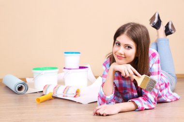 Güzel kız boyama duvar için ekipman ile yerde yatarken