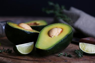 Avokado kireç ve bitki ile kesme tahtası siyah arka plan üzerine dilimlenmiş