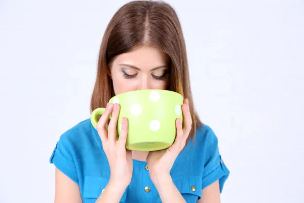 Beautiful girl drinks from large cup — Stock Photo, Image