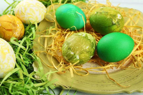 Composición de Pascua con huevos coloridos en plato sobre fondo de mesa de madera —  Fotos de Stock