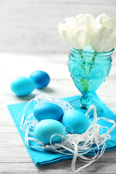 Velikonoční složení s barevnými vejci na ubrousek na dřevěný stůl pozadí — Stock fotografie