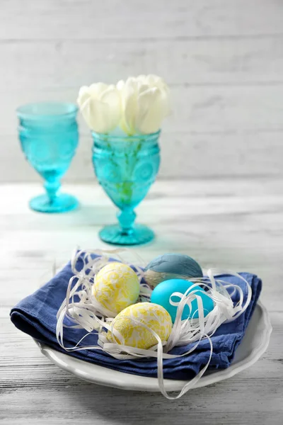Plakaları ahşap masa arka plan üzerinde renkli yumurta ile Paskalya kompozisyon — Stok fotoğraf
