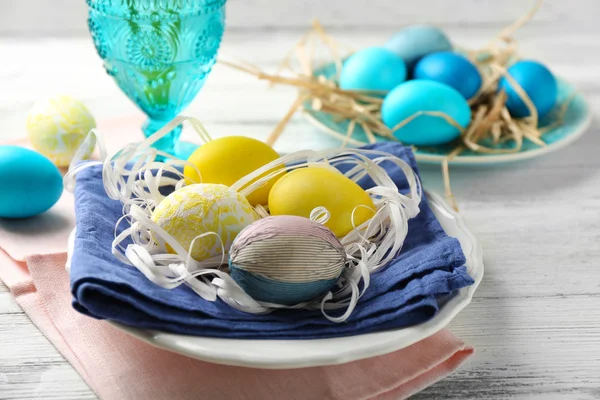 Pasen samenstelling met kleurrijke eieren op platen op houten tafel achtergrond — Stockfoto