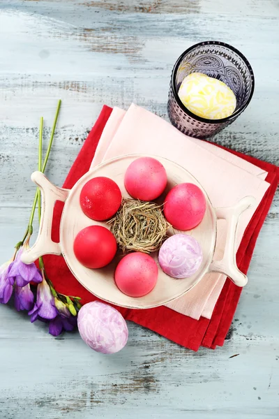 Composición de Pascua con huevos de colores en el soporte sobre fondo de mesa de madera — Foto de Stock