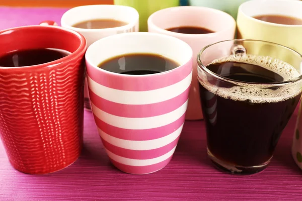 Muitas xícaras de café na tabela de cores, close-up — Fotografia de Stock