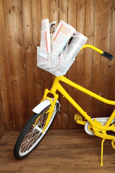 Vintage vélo jaune avec journal et colis, sur fond de mur en bois — Photo