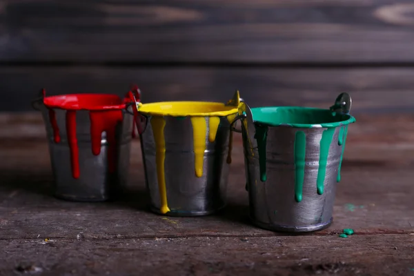 Baldes de metal com tinta colorida sobre fundo de madeira — Fotografia de Stock