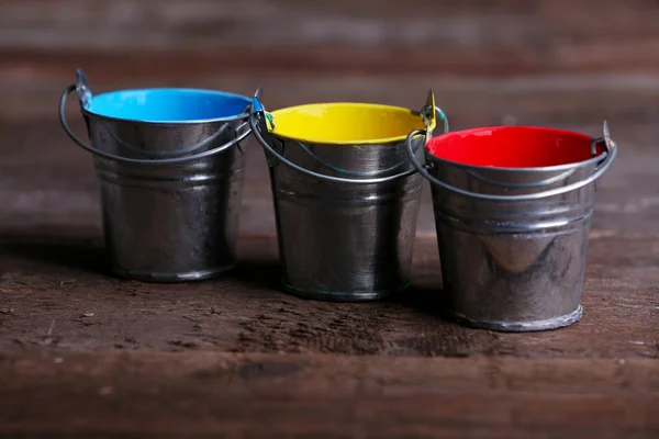 Baldes de metal com tinta colorida sobre fundo de madeira — Fotografia de Stock