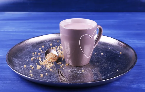 Tazza di cacao con cucchiaio di zucchero su vassoio di metallo su sfondo di legno a colori — Foto Stock