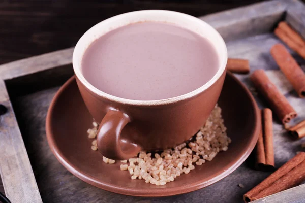 Чашка какао с сахаром и корицей на деревянном подносе, крупный план — стоковое фото
