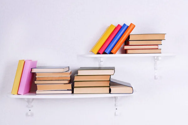 Books on shelves on white wall background — Stock Photo, Image