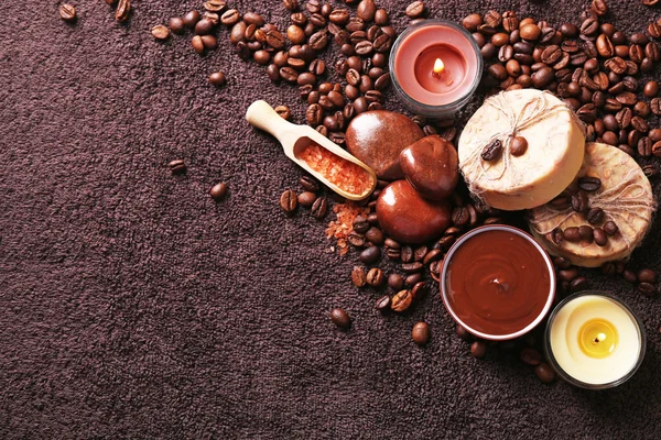 Состав мыла, шоколада в миске и кофейных зерен на фоне коричневого полотенца — стоковое фото