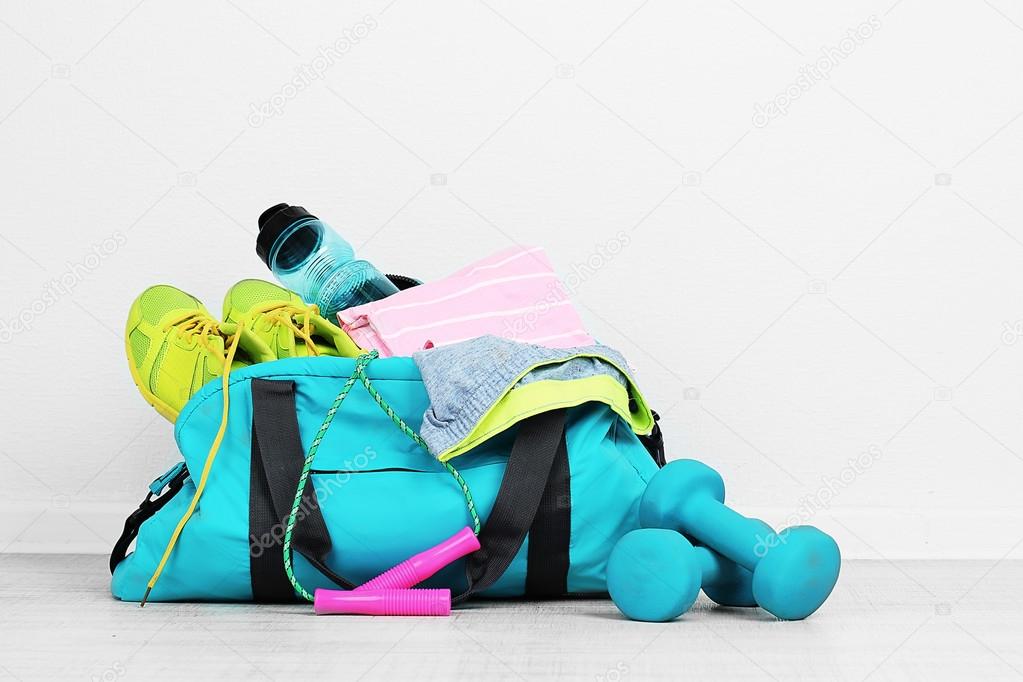 Sports bag with sports equipment in room