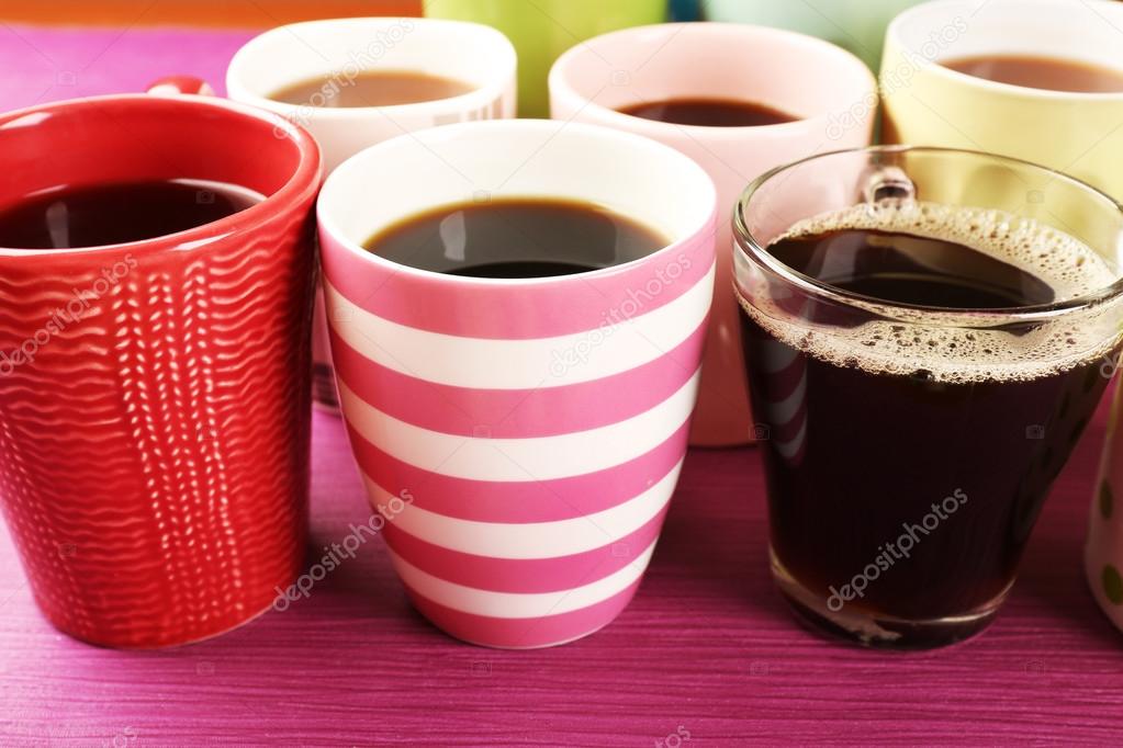 Many cups of coffee on color table, closeup