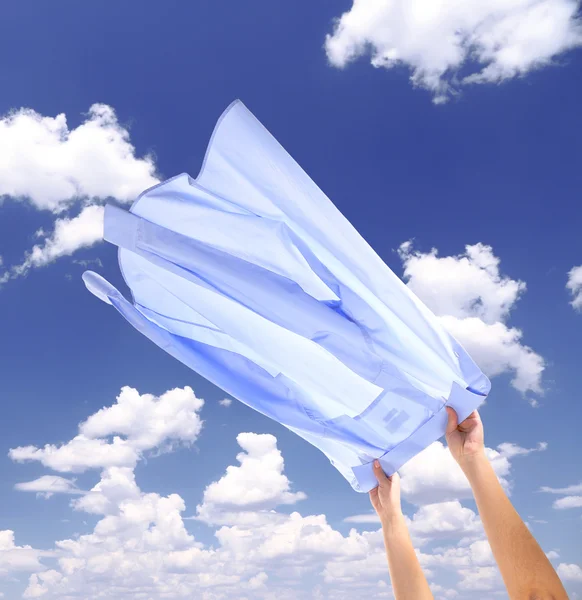 Hands holding flying shirt on sky background — Stock Photo, Image