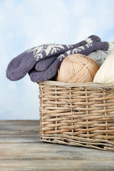 Knitting yarn and mittens in basket, on light background — Stock Photo, Image