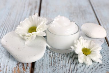 Çiçek ve spa taşlar ahşap arka plan üzerinde kozmetik krem