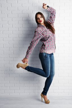 Güzel kız beyaz tuğla duvar arka plan üzerinde poz rahat tarzı giyinmiş