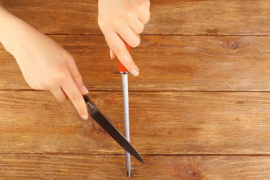 Ahşap arka plan üzerinde bıçak işlemi keskinleştirme