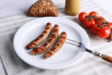 Ekmek ile plaka üzerinde ızgara sosis ve domates tablo üzerinde kapat