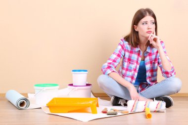 Güzel kız boyama duvar için ekipman ile katta oturan