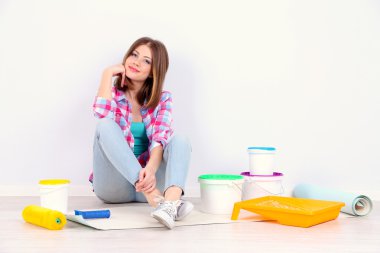 Güzel kız boyama duvar için ekipman ile katta oturan