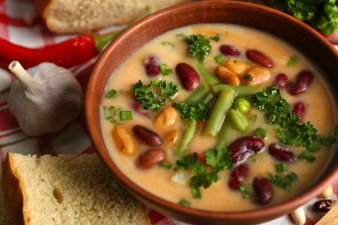 Peçete, ahşap masa arka plan üzerinde taze dilimlenmiş ekmek kase fasulye çorbası