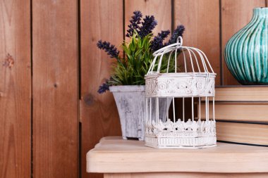 İç tasarım dekoratif vazo, kafes, bitki ve masa üstü ahşap plakalar arka plan üzerinde üzerinde kitap yığını